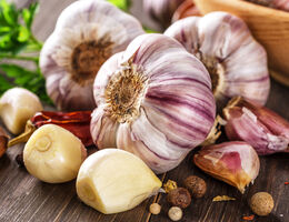 Garlic cloves, peeled and unpeeled, on a wooden surface.