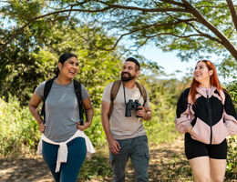 A man and two women smile as they walk through a nature area.