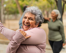 An older woman smiles as she stretches.