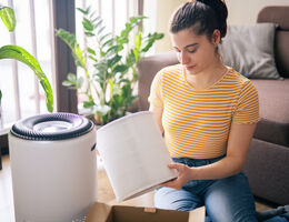A woman changes the filter on a home air purifier.