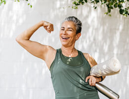 An older woman flexes her bicep.