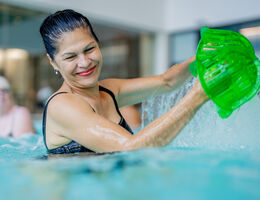 A woman smiles while exercising in a pool.