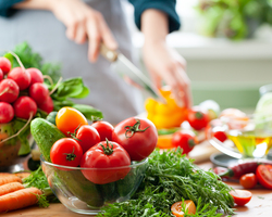 Bunches of radishes, carrots, tomatoes, cucumbers, lettuce and peppers cover a countertop.