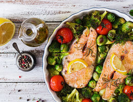 A bowl of vegetables with two fillets of salmon on top.