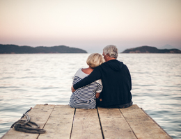 A older couple sit on a dock