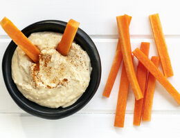 Carrot sticks and a bowl of hummus.